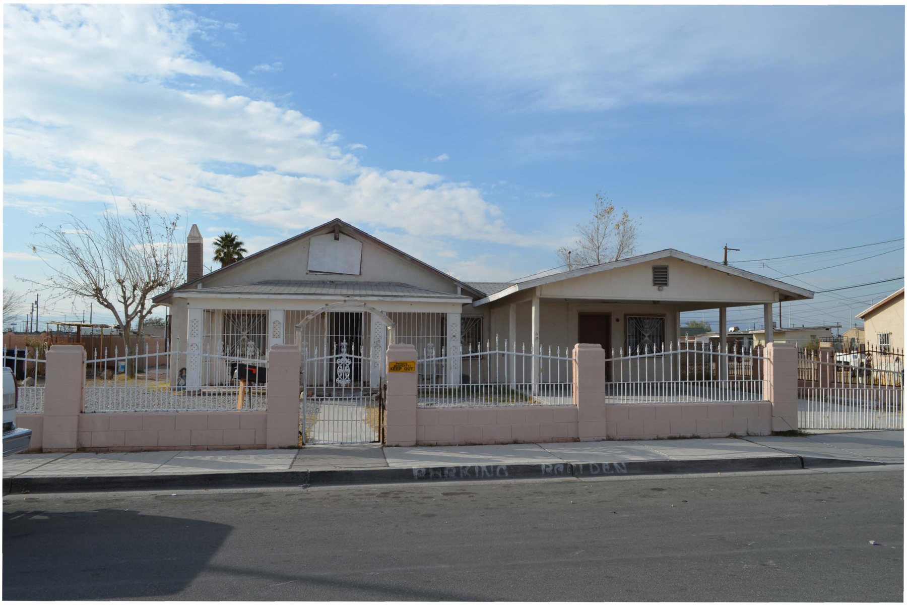 The east facade of Harrison's Guest House at 1001 F Street, Las Vegas, a single-story bungalow behind a low block and iron fence.
